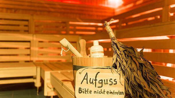 Blick in die Sauna: Ein Eimer, Wedel und ein Schild mit Schriftzug "Aufguss; Bitte nicht eintreten".