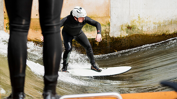 Ein Surfer auf der Leinewelle, der auf dem Brett steht.