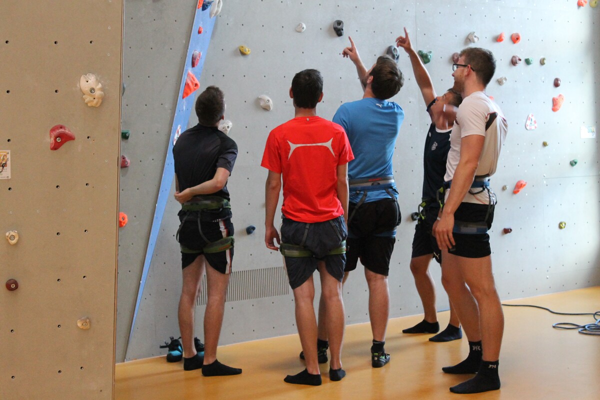 Gruppe von Kletternden, die die Kletterwand anschauen.