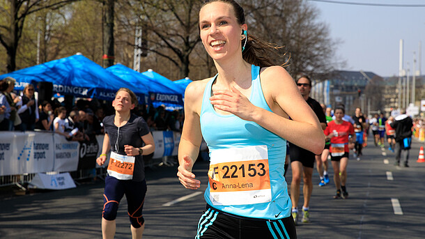 Eine Marathon Teilnehmerin läuft strahlend die Strecke entlang.