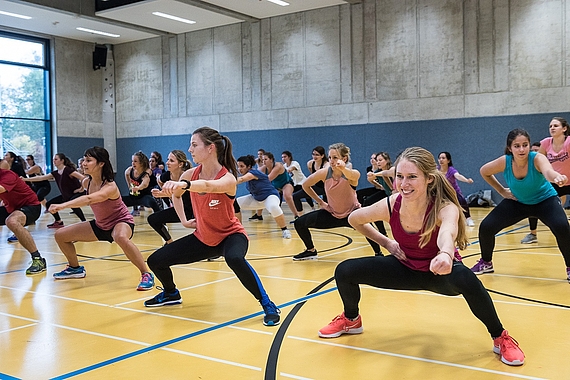 Mehrere Personen trainieren gemeinsam in einer Sporthalle.