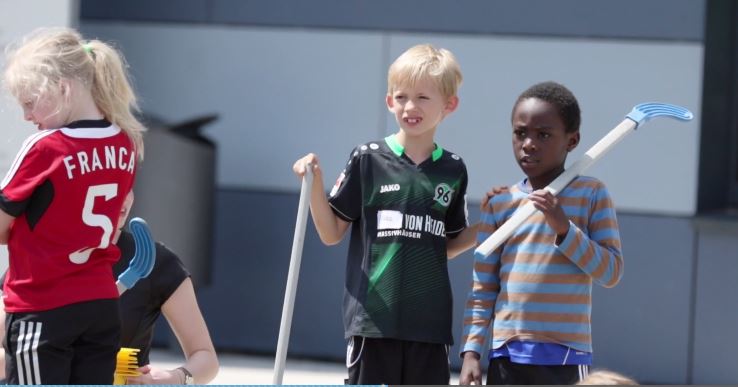 Drei Kinder halten Hockeyschläger.