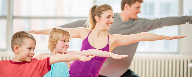 Eine Familie praktiziert gemeinsam Yoga.