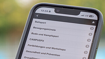 Handy auf dem das Sportprogramm sortiert nach Sportbereichen angezeigt wird.