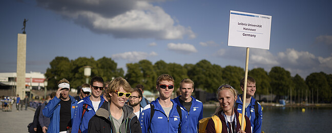 Athleten_innen halten ein Schild mit dem Text Leibniz Universität Hannover Germany hoch.