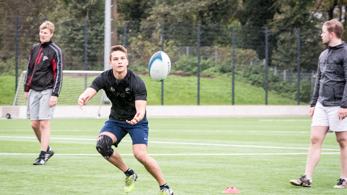 Ein Rugbyspieler hat die Arme ausgestreckt um den Ball zu fangen