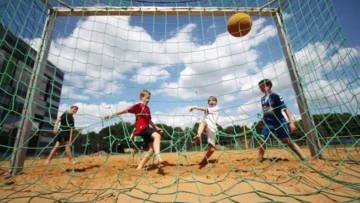 Eine Gruppe Kinder schießt einen Ball in ein Tor.