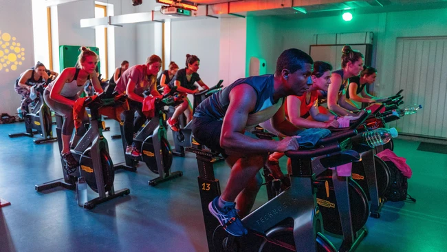 Eine Übungsleiterin führt eine Zumba Bewegung auf einem Aerobic-Step aus
