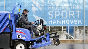 ein technischer Mitarbeiter sitzt auf einer Säuberungsmaschine und fährt über den SportCAMPUS