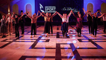 Tänzer*innen des Lindy Hops halten ihre Hände in die Höhe nach ihrem Autritt im Lichthof des Welfenschlosses der LUH