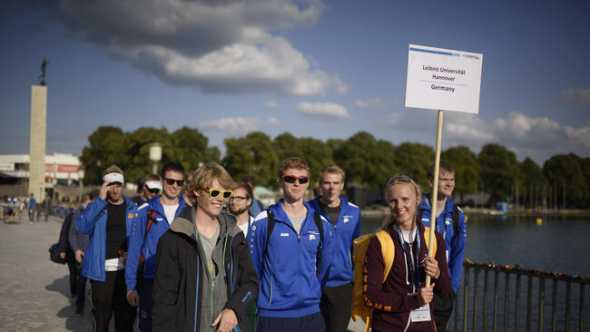 Athleten_innen halten ein Schild mit dem Text Leibniz Universität Hannover Germany hoch.